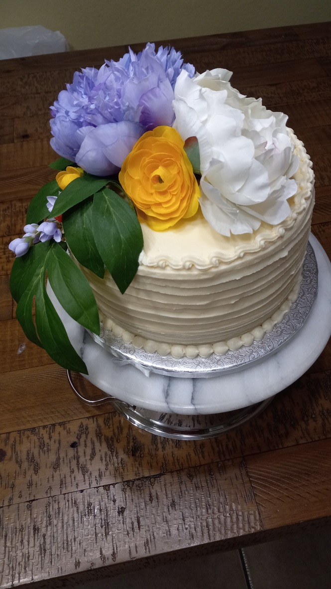 White cake decorated with lavender, white, and yellow flowers
