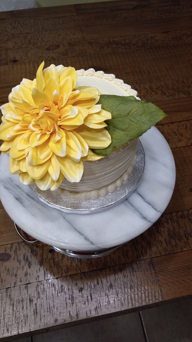White cake decorated with a large yellow flower